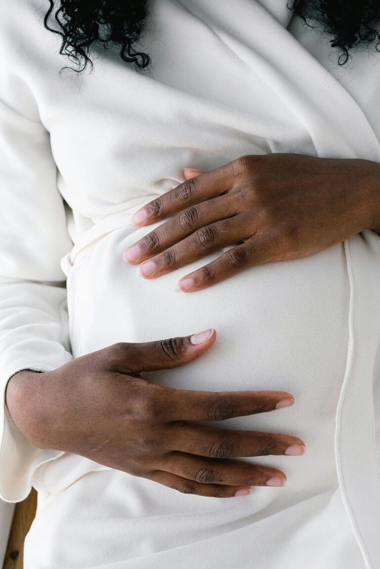 Black women holding her pregnancy belly in a white long sleeve shirt | Stories of Hope | Mary's Refuge | Martinsburg WV