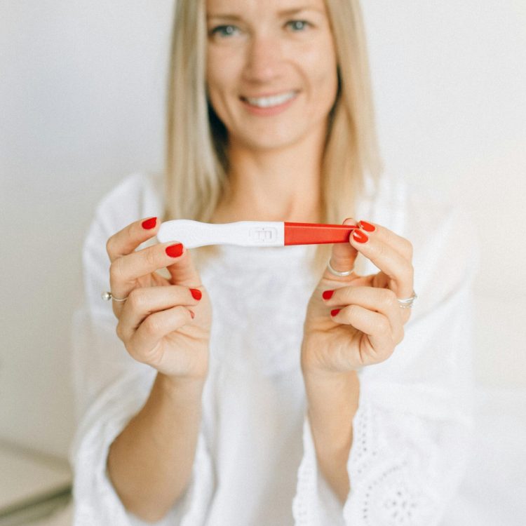 Women smiling and holding up a positive pregnancy test | Positive Pregnancy Test | Mary's Refuge, Martinsburg WV